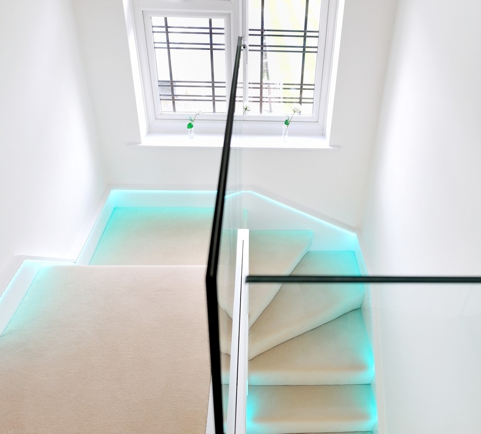 Inspiration pour un grand escalier design en U avec des marches en moquette, des contremarches en verre et un garde-corps en verre.