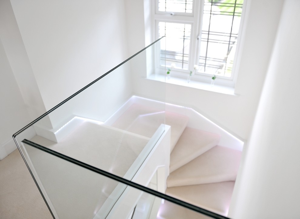 На фото: большая п-образная лестница в современном стиле с ступенями с ковровым покрытием, стеклянными подступенками и стеклянными перилами