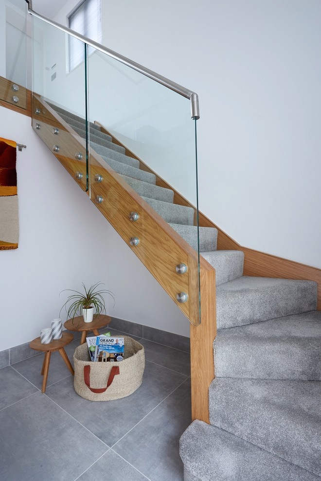 Пример оригинального дизайна: изогнутая лестница среднего размера в современном стиле с деревянными ступенями, стеклянными подступенками и стеклянными перилами
