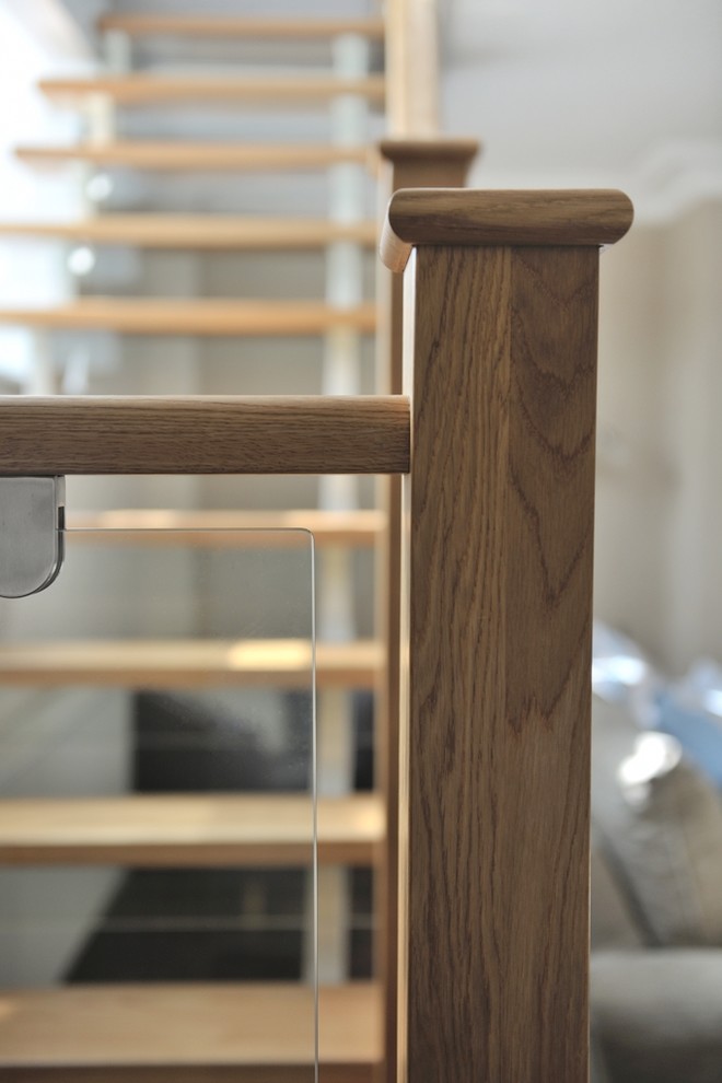 カーディフにある中くらいなコンテンポラリースタイルのおしゃれなかね折れ階段 (ガラスの蹴込み板、木材の手すり) の写真