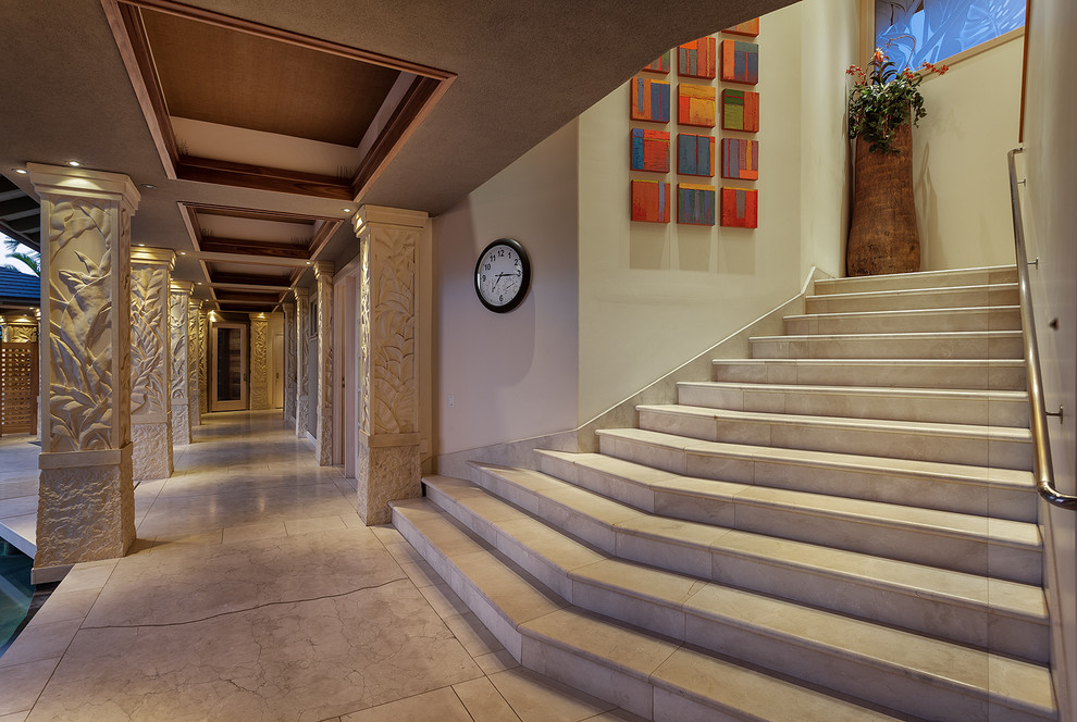 Large world-inspired curved staircase in Hawaii with limestone treads and limestone risers.