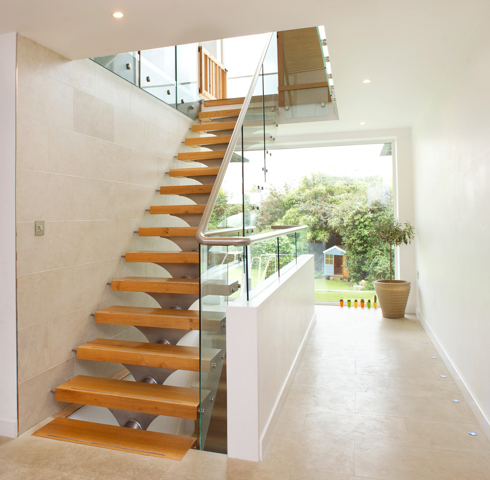 На фото: большая прямая лестница в современном стиле с деревянными ступенями и стеклянными перилами без подступенок с