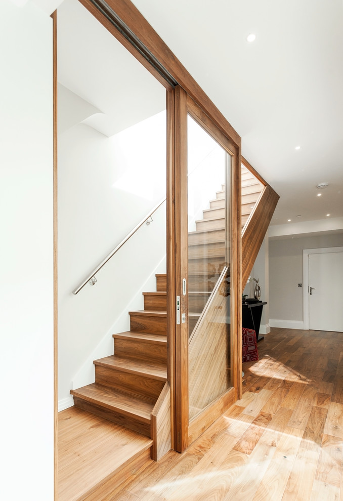 Photo of a contemporary wood straight staircase in London with wood risers.