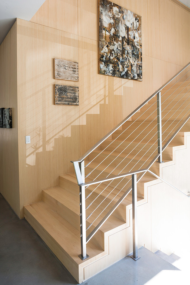 Design ideas for a contemporary wood wire cable railing staircase in New York with wood risers and feature lighting.