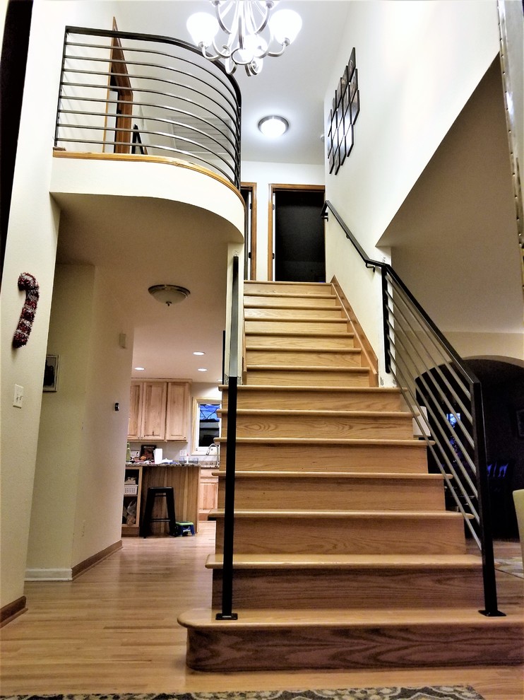 Diseño de escalera curva contemporánea grande con escalones de madera y barandilla de metal