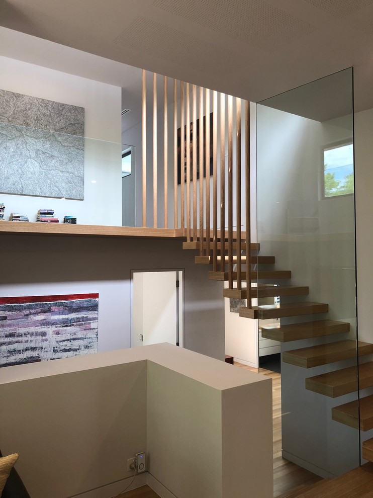 Imagen de escalera en U contemporánea sin contrahuella con escalones de madera y barandilla de vidrio