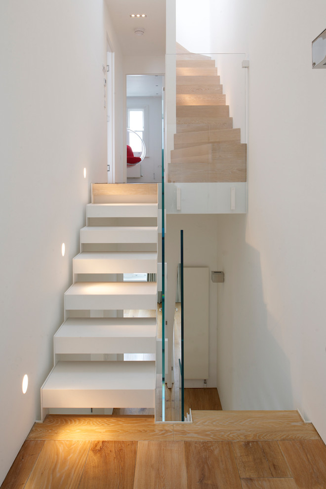 Exempel på en mellanstor modern flytande trappa i trä, med öppna sättsteg och räcke i glas
