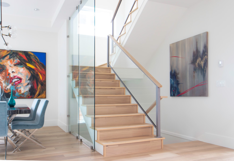 Cette image montre un escalier design en U de taille moyenne avec des marches en bois, des contremarches en bois et un garde-corps en verre.