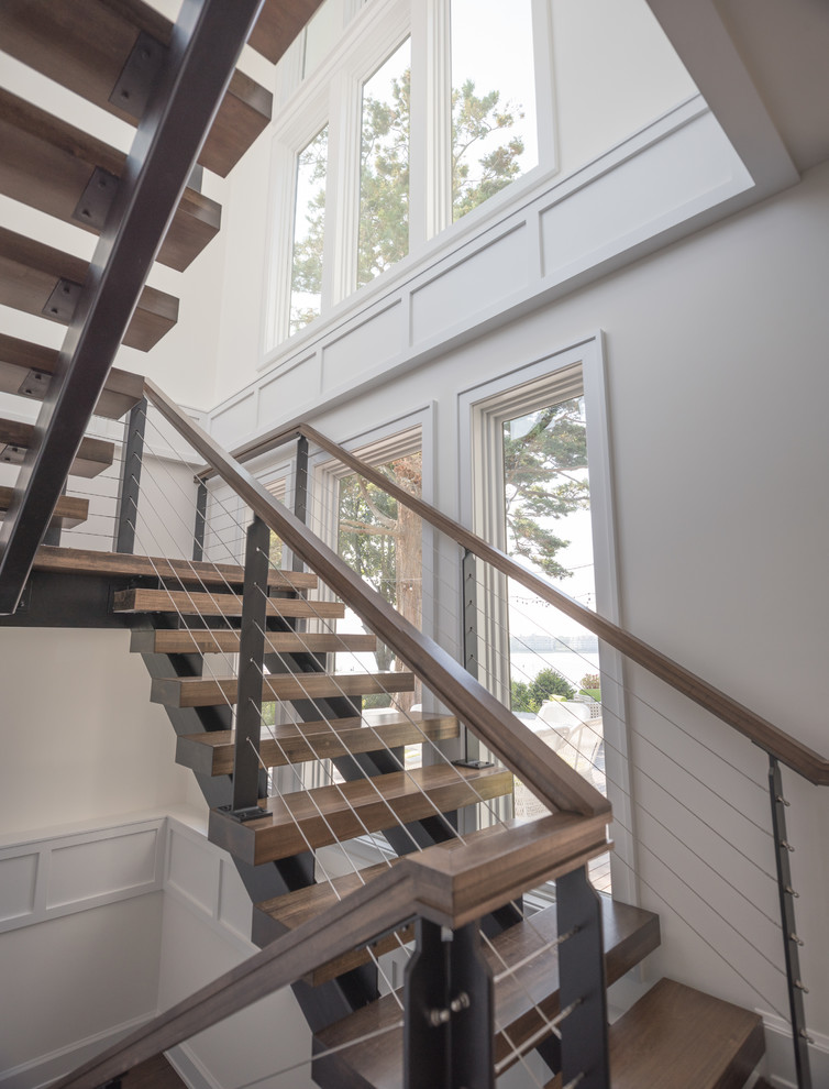 Imagen de escalera en U contemporánea con escalones de madera, contrahuellas de metal y barandilla de madera