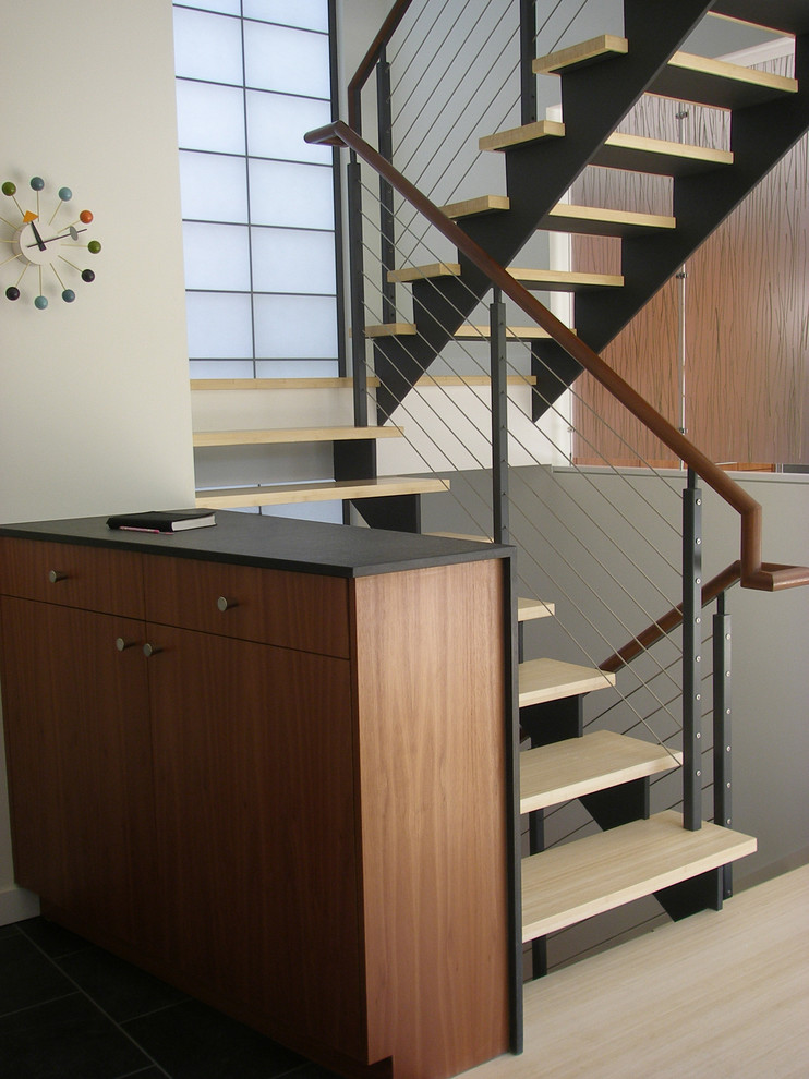Cette image montre un escalier sans contremarche design avec des marches en bois et un garde-corps en câble.