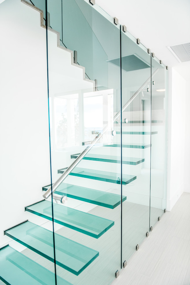 На фото: лестница на больцах в современном стиле с стеклянными ступенями и стеклянными перилами без подступенок
