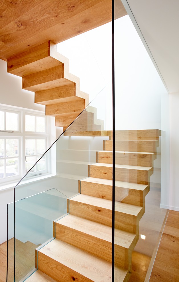Exempel på en modern rak trappa i trä, med sättsteg i trä och räcke i glas