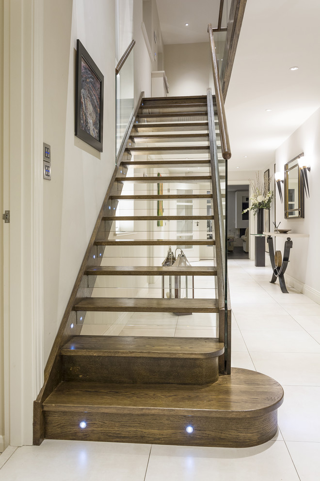 Imagen de escalera recta actual de tamaño medio con escalones de madera, contrahuellas de vidrio y barandilla de varios materiales