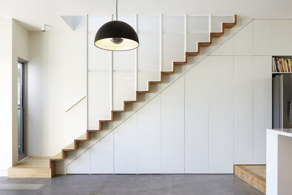 Cette image montre un escalier droit design avec des marches en bois, des contremarches en bois et rangements.