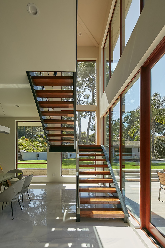 Свежая идея для дизайна: п-образная лестница в современном стиле с деревянными ступенями и стеклянными перилами без подступенок - отличное фото интерьера
