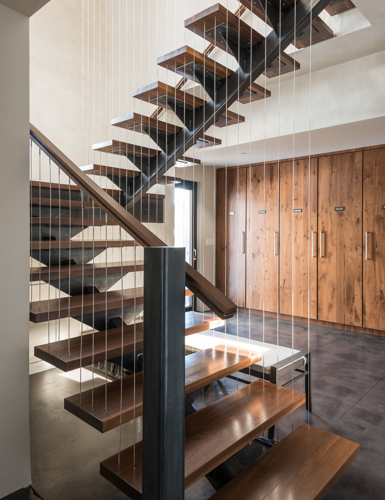 На фото: лестница в современном стиле с деревянными ступенями и перилами из тросов без подступенок