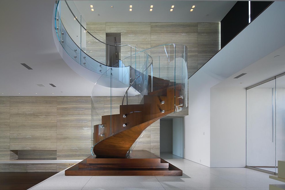 Aménagement d'un escalier hélicoïdal contemporain avec des contremarches en bois, des marches en bois, un garde-corps en verre et palier.