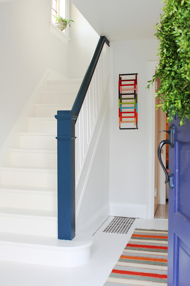 Ejemplo de escalera en L actual con escalones de madera pintada y contrahuellas de madera pintada