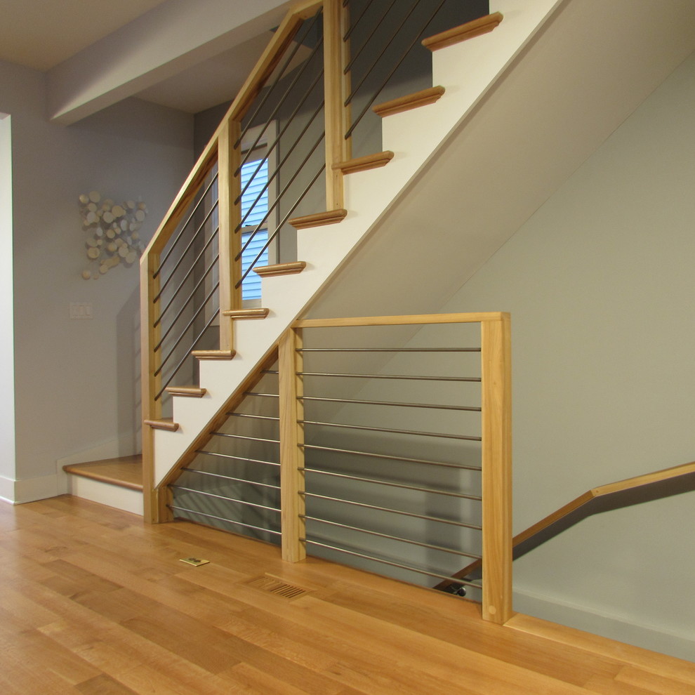 Imagen de escalera recta actual de tamaño medio con escalones de madera, barandilla de metal y contrahuellas de madera pintada