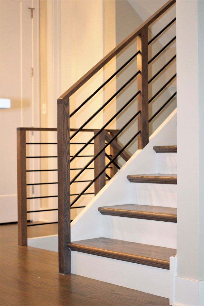 Imagen de escalera actual con escalones de madera, barandilla de metal y contrahuellas de madera pintada