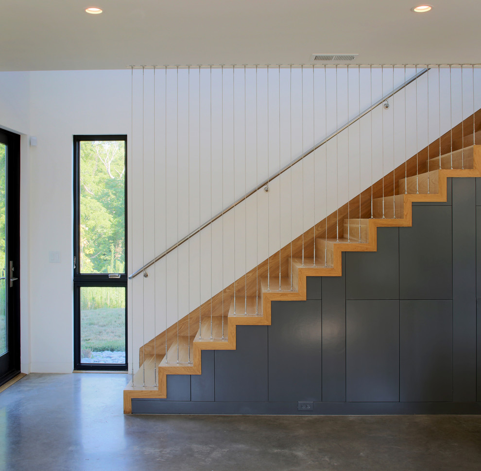 Cette photo montre un escalier droit tendance de taille moyenne avec des marches en bois, des contremarches en bois et un garde-corps en métal.