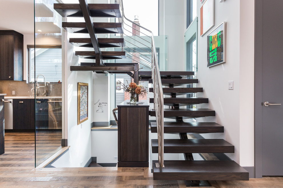 Cette image montre un grand escalier design en U avec des marches en bois et un garde-corps en métal.