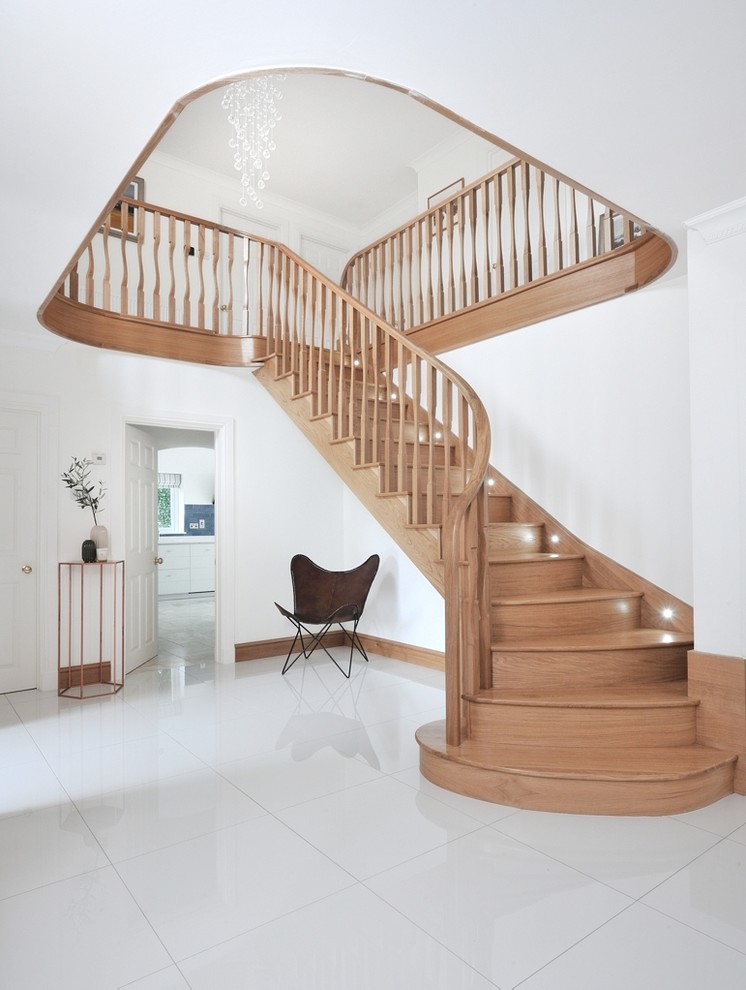 Aménagement d'un grand escalier courbe contemporain avec des marches en bois, des contremarches en bois et un garde-corps en bois.