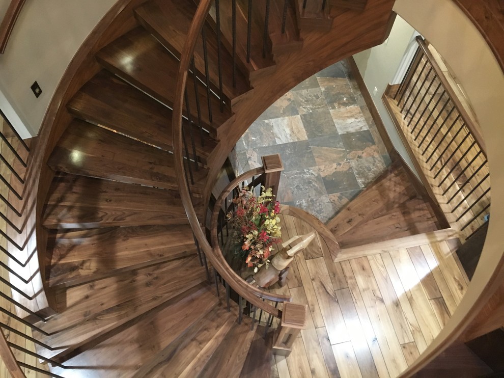 Cette image montre un grand escalier sans contremarche courbe traditionnel avec des marches en bois et un garde-corps en bois.