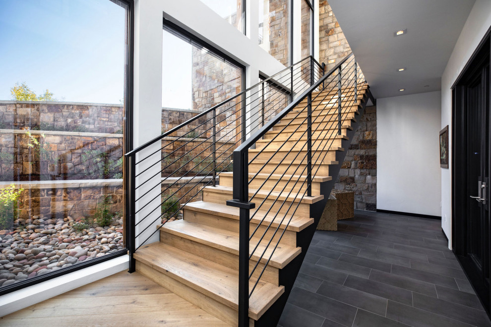 デンバーにある高級な広いコンテンポラリースタイルのおしゃれな直階段 (木の蹴込み板、金属の手すり) の写真