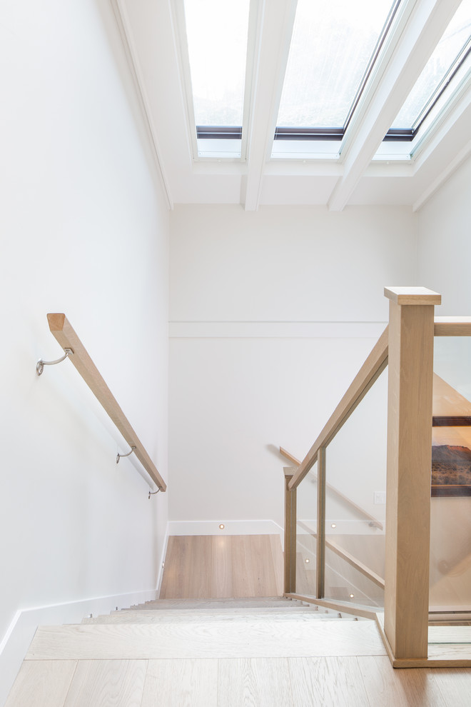 Свежая идея для дизайна: угловая лестница среднего размера в стиле неоклассика (современная классика) с деревянными ступенями, крашенными деревянными подступенками и стеклянными перилами - отличное фото интерьера