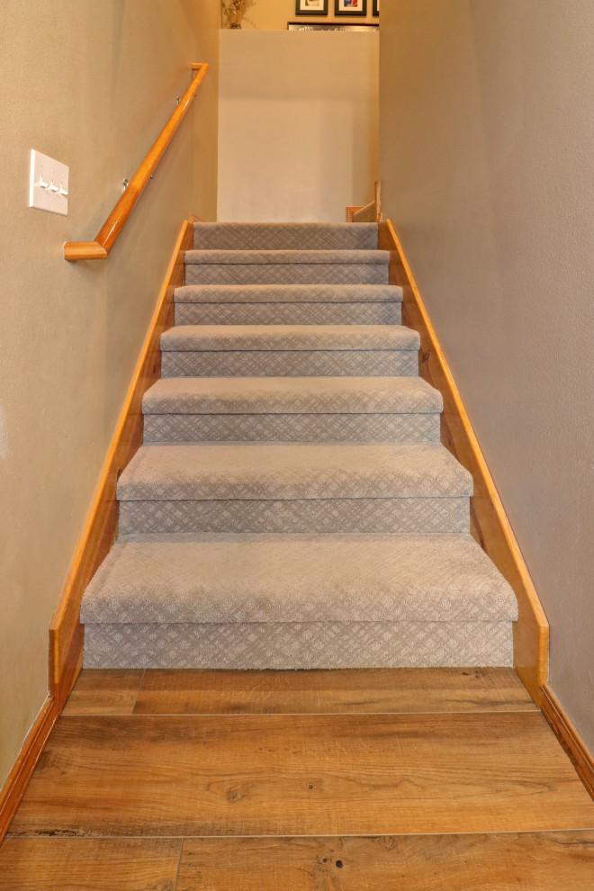 Cette photo montre un escalier chic en U avec des marches en moquette, des contremarches en moquette et un garde-corps en bois.