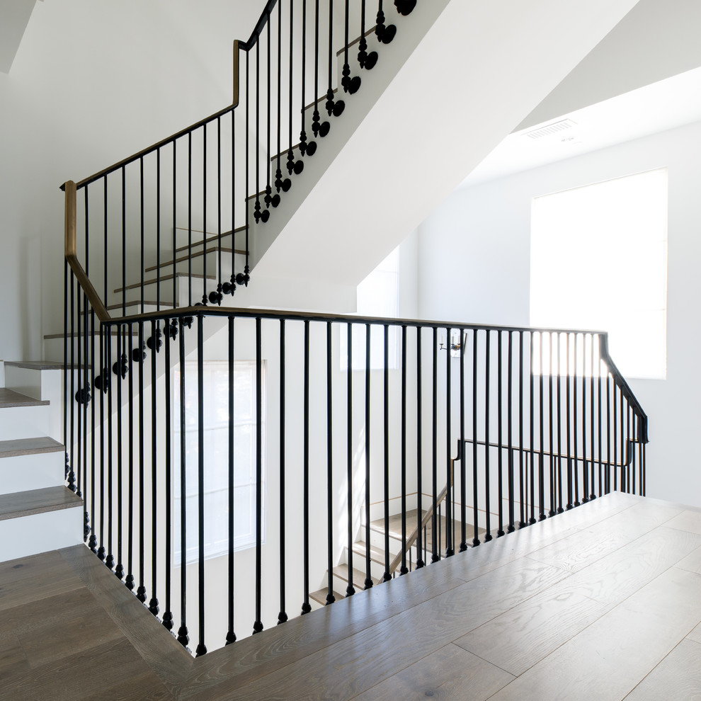 Idée de décoration pour un grand escalier peint design en U avec des marches en bois et un garde-corps en bois.
