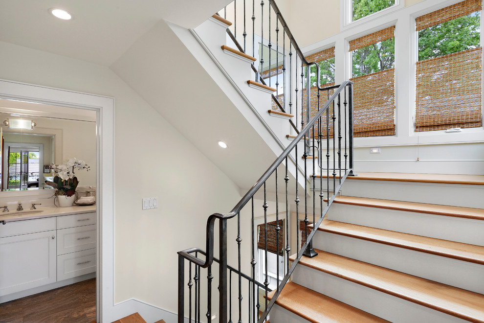 Example of a mid-sized transitional wooden curved staircase design in Orange County with metal risers