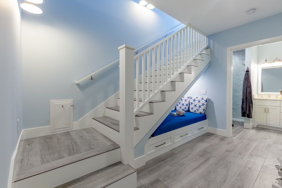 This is an example of a beach style tiled l-shaped wood railing staircase in San Diego with painted wood risers and feature lighting.