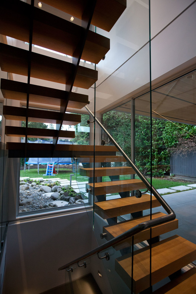 Diseño de escalera suspendida moderna grande con escalones de madera y contrahuellas de metal