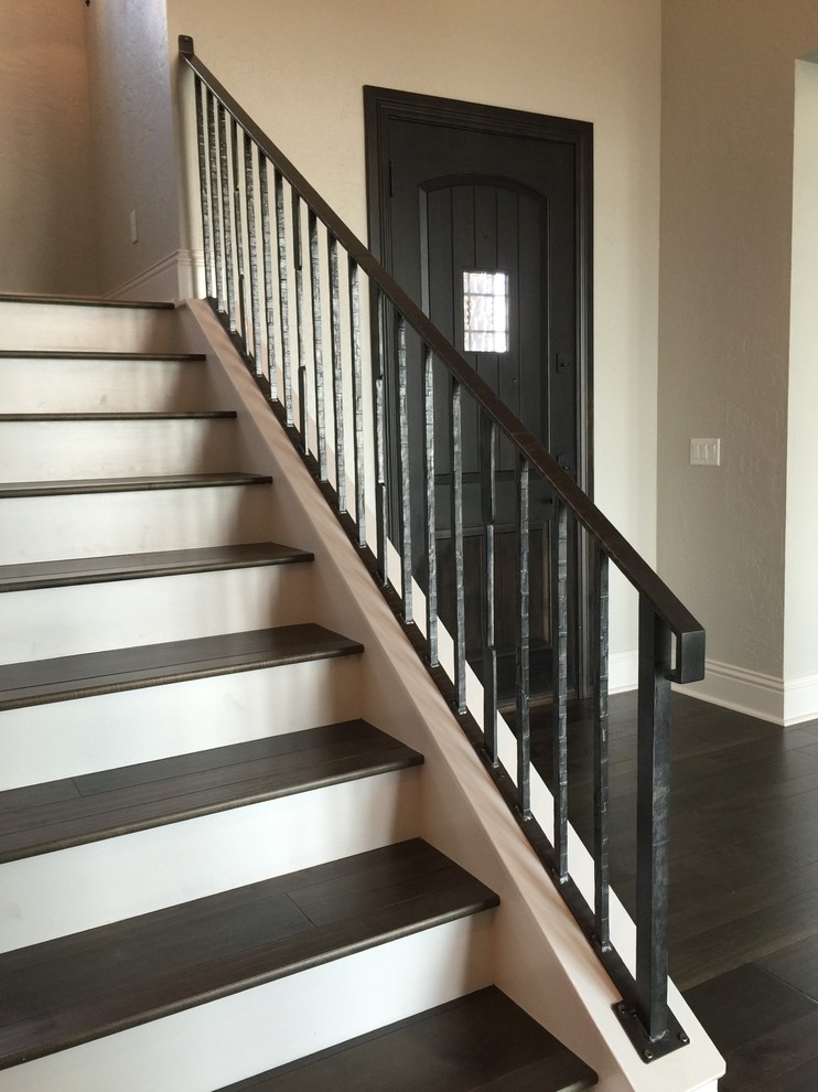 Imagen de escalera en U clásica de tamaño medio con escalones de madera, contrahuellas de madera pintada y barandilla de metal