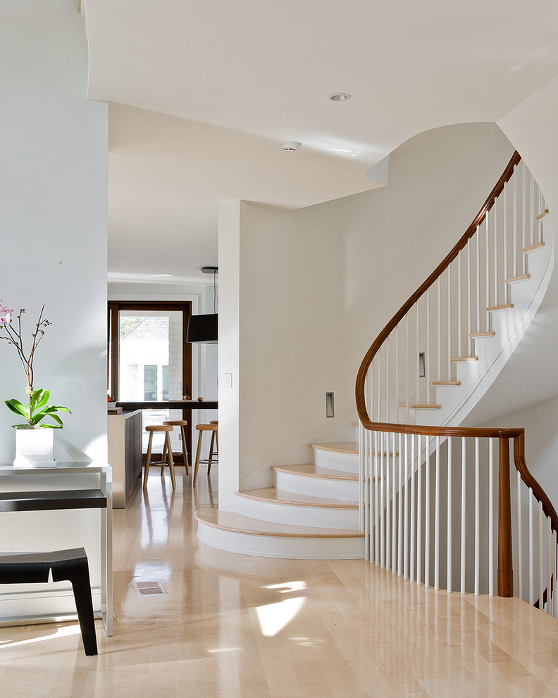 Идея дизайна: изогнутая лестница в современном стиле с деревянными ступенями, крашенными деревянными подступенками и деревянными перилами