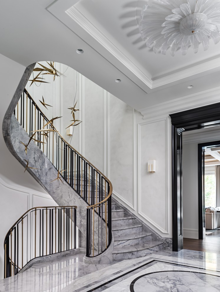 Imagen de escalera curva clásica renovada extra grande con escalones de mármol, contrahuellas de mármol y barandilla de metal