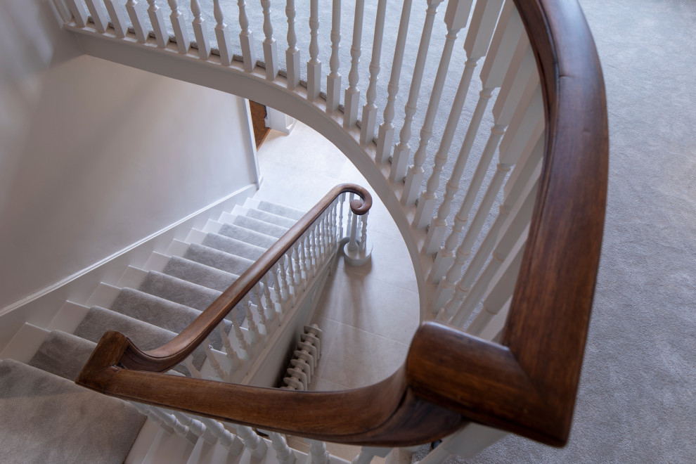 Imagen de escalera curva actual grande con escalones enmoquetados, contrahuellas enmoquetadas y barandilla de madera