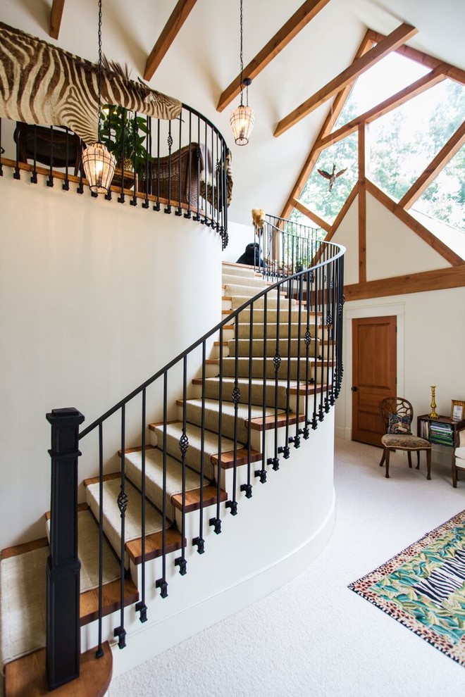 Diseño de escalera curva clásica renovada con escalones de madera, contrahuellas de madera pintada y barandilla de metal
