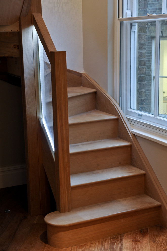 Staircase - mid-sized modern wooden curved staircase idea in London with wooden risers