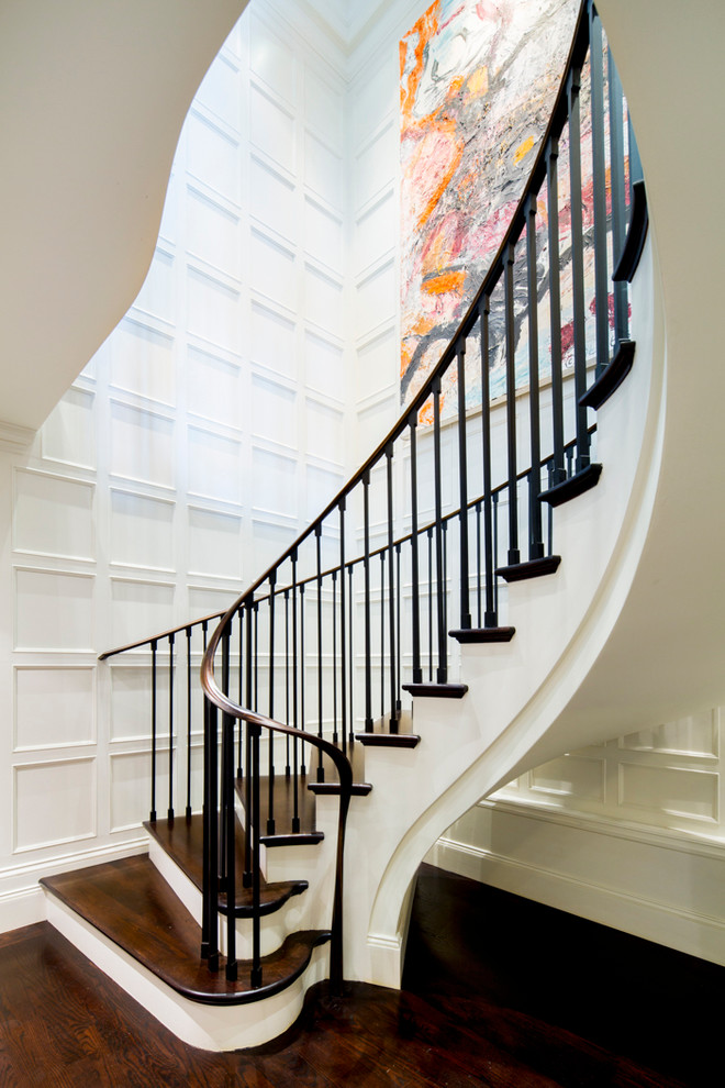 На фото: изогнутая лестница в классическом стиле с деревянными ступенями и крашенными деревянными подступенками