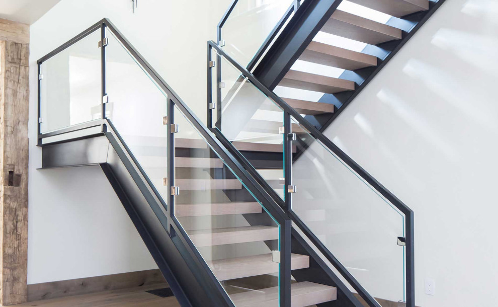 На фото: угловая лестница в стиле рустика с деревянными ступенями, стеклянными подступенками и металлическими перилами с