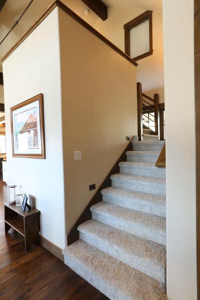 На фото: большая угловая деревянная лестница в стиле рустика с ступенями с ковровым покрытием и перилами из смешанных материалов