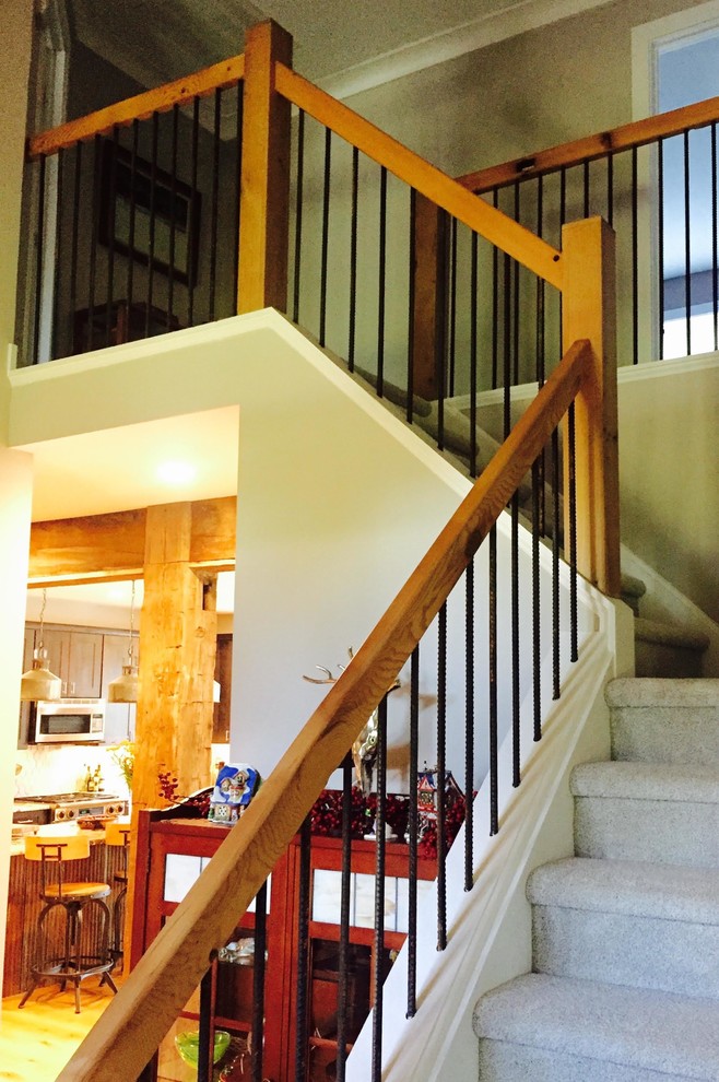 На фото: угловая лестница среднего размера в стиле кантри с ступенями с ковровым покрытием, ковровыми подступенками и деревянными перилами