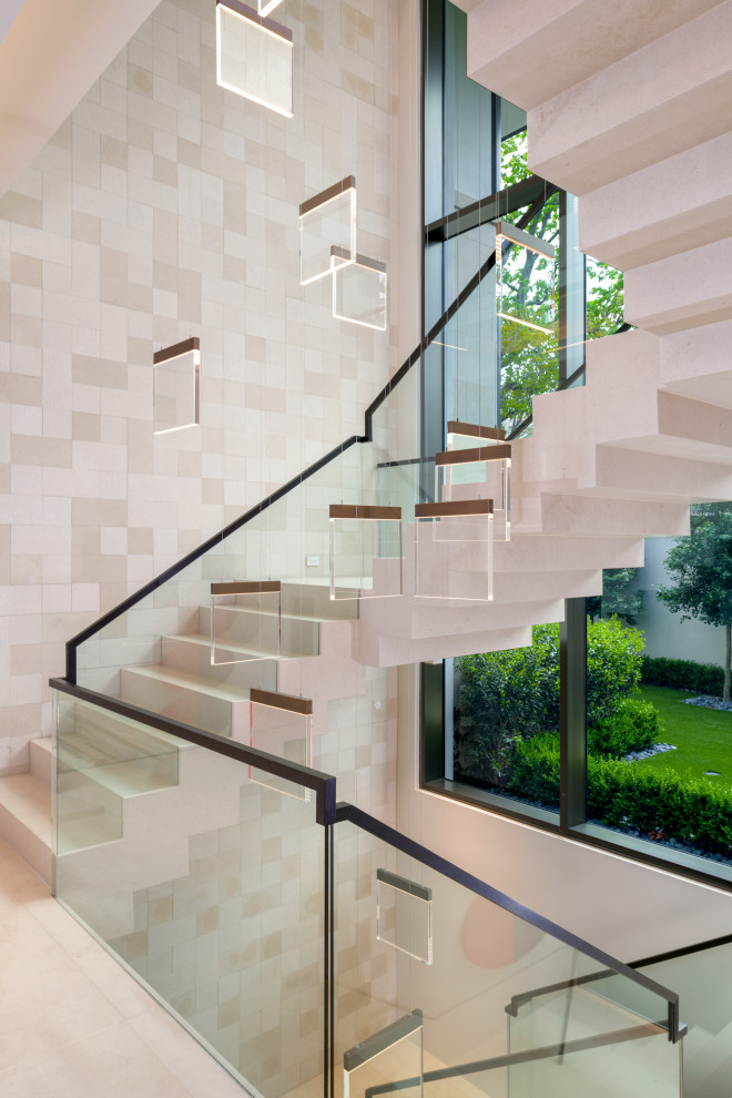 Idée de décoration pour un grand escalier carrelé courbe design avec des contremarches carrelées et un garde-corps en verre.