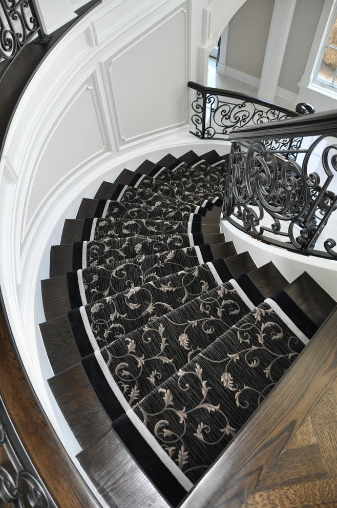 This is an example of a large classic wood curved staircase in New York with painted wood risers.