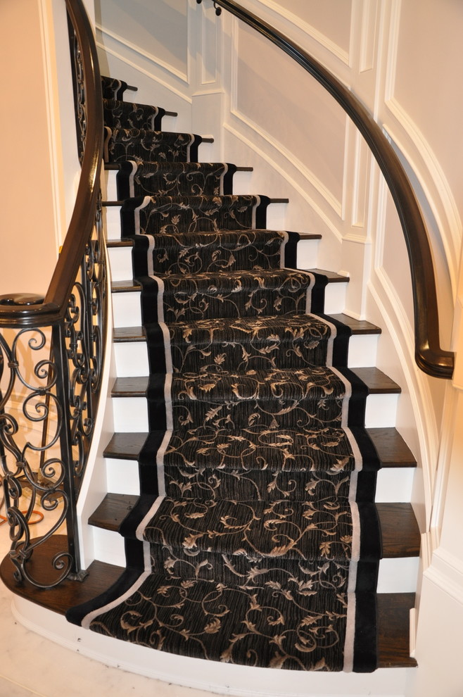 Aménagement d'un grand escalier peint courbe classique avec des marches en bois.