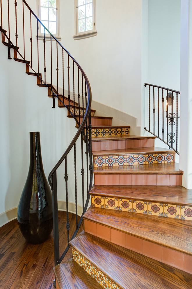 Пример оригинального дизайна: изогнутая лестница в средиземноморском стиле с деревянными ступенями и подступенками из плитки