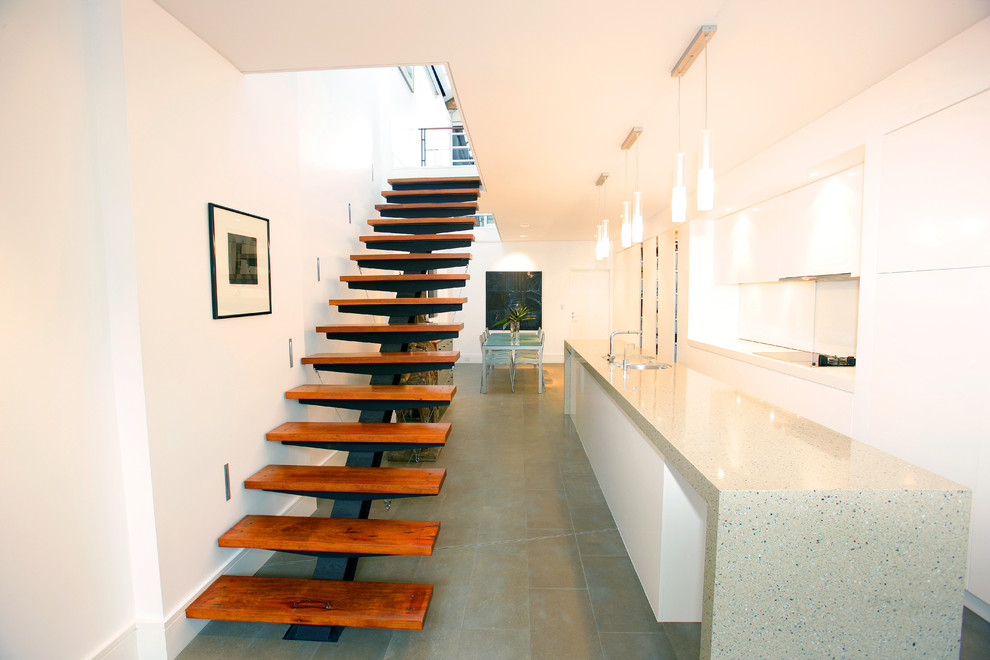 Réalisation d'un escalier flottant design avec des marches en bois et des contremarches en métal.